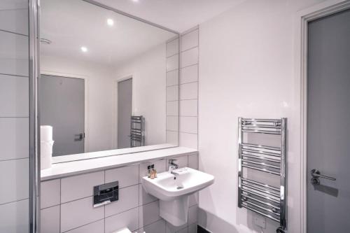Baño blanco con lavabo y espejo en Spacious 1 Bed Apartment in Central Manchester en Mánchester