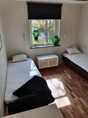 a small bedroom with two beds and a window at Forenom Hostel Lund Örtofta in Eslöv