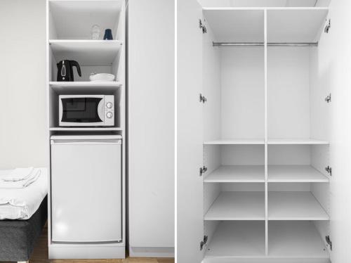 a kitchen with white cabinets and a microwave at Forenom Hostel Lund Örtofta in Eslöv