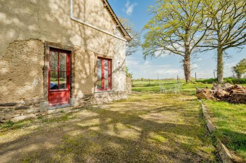 an old stone house with red doors in a field at Maison de campagne Rennes Parc Expo in Mordelles