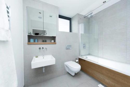 a bathroom with a toilet and a sink and a tub at Modern 2 Bed Apartment w Balcony in London in London