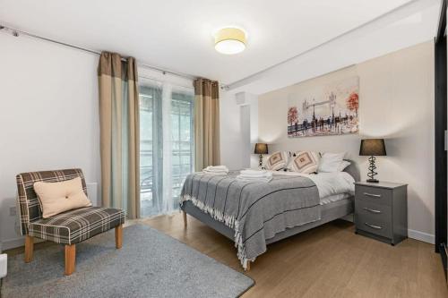 a bedroom with a bed and a chair and a window at Modern 1 Bedroom Apartment in Woking Town Centre in Woking
