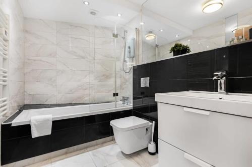 a bathroom with a tub and a toilet and a sink at Modern 1 Bedroom Apartment in Woking Town Centre in Woking