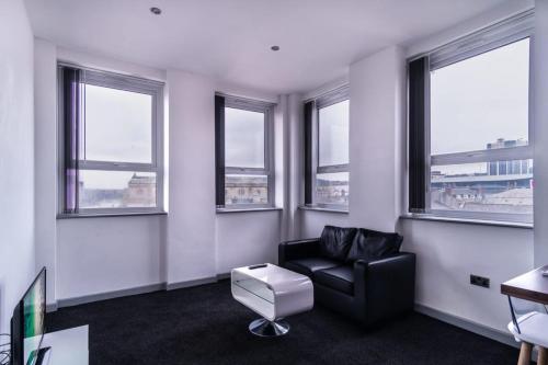 Contemporary 1 Bed Apartment in Central Blackburn في بلاكبيرن: غرفة معيشة مع كرسي أسود ونوافذ