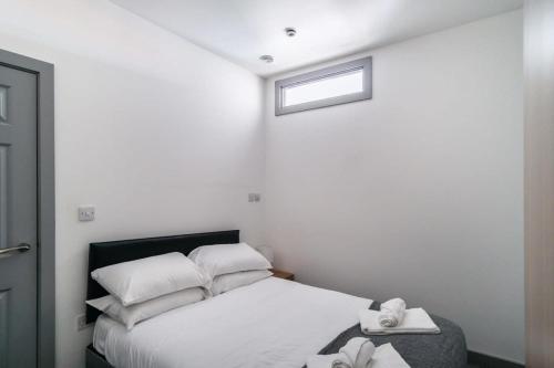 a bedroom with a bed with white pillows and a window at Smart 1 Bedroom Apartment in Blackburn in Blackburn
