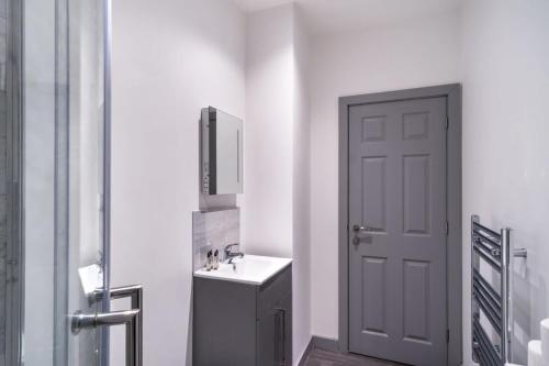 a white bathroom with a sink and a door at Smart 1 Bedroom Apartment in Blackburn in Blackburn