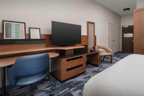 a room with a desk with a tv and a blue chair at Fairfield Inn & Suites by Marriott Ithaca in Ithaca