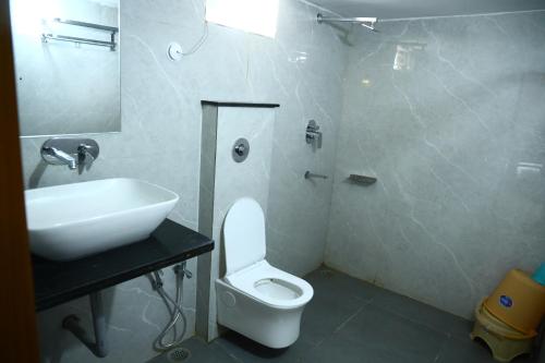 La salle de bains est pourvue de toilettes blanches et d'un lavabo. dans l'établissement Shree Tara Heritage, à Sānchi