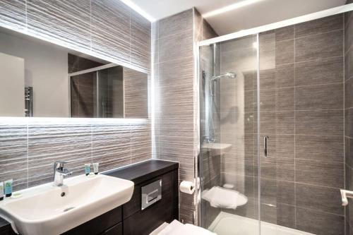 a bathroom with a sink and a glass shower at Stunning 2 Bed Apartment in Central Manchester in Manchester