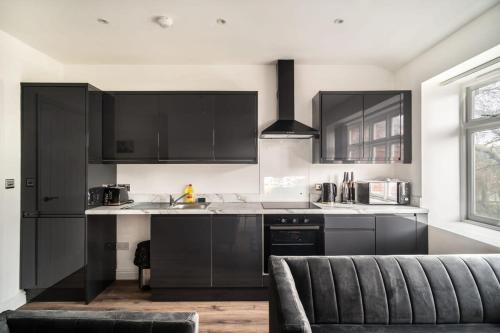 a kitchen with black cabinets and a gray couch at Spacious 2 Bed Apartment in Waterloo Liverpool in Waterloo
