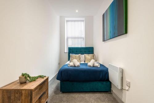 a bedroom with a blue bed and a couch at Smart 2 Bed Budget Apartment in Central Doncaster in Doncaster