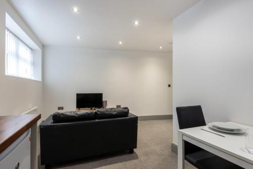 a living room with a black couch and a tv at Cosy 1 Bed Budget Flat in Central Darlington in Darlington