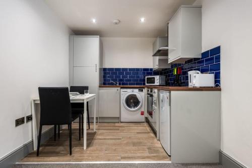 a kitchen with a washing machine and a table with chairs at Cosy 1 Bed Budget Flat in Central Darlington in Darlington