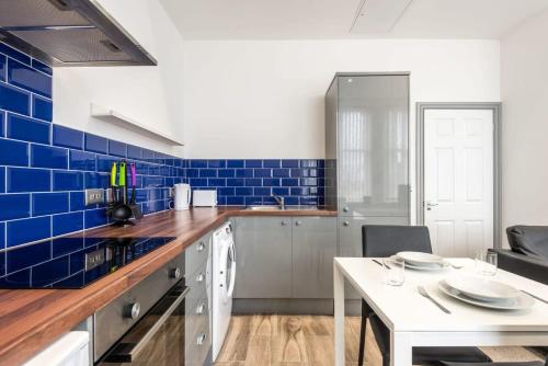 a kitchen with blue tiles on the wall and a table at Lovely 1 Bed Budget Apartment in Central Darlington in Darlington