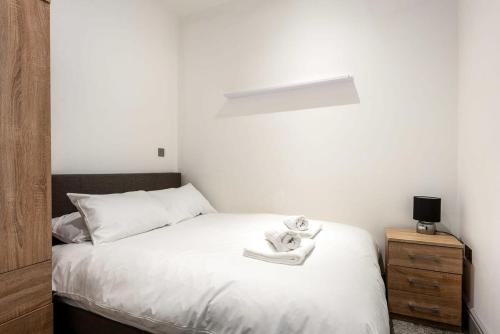 ein Schlafzimmer mit einem weißen Bett und einem Nachttisch in der Unterkunft Lovely 1 Bed Budget Apartment in Central Darlington in Darlington
