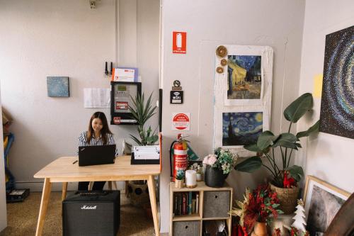 eine Frau, die an einem Schreibtisch mit einem Laptop sitzt in der Unterkunft CarricHostel in Melbourne