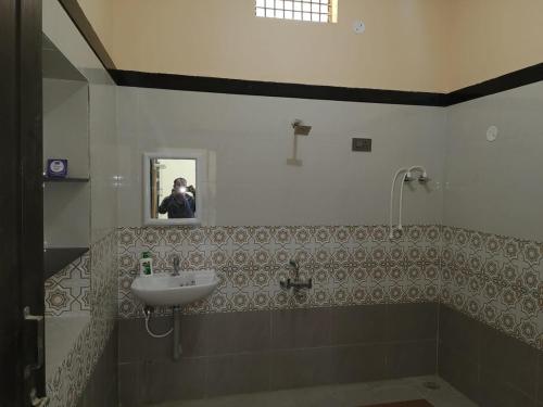 a person taking a picture of a bathroom with a sink at Sagar Homestay Hampi in Hampi
