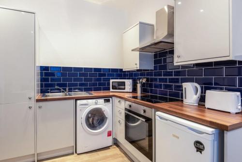 a kitchen with a washer and dryer and blue tiles at Modern 1 Bed Budget Apartment in Darlington in Darlington