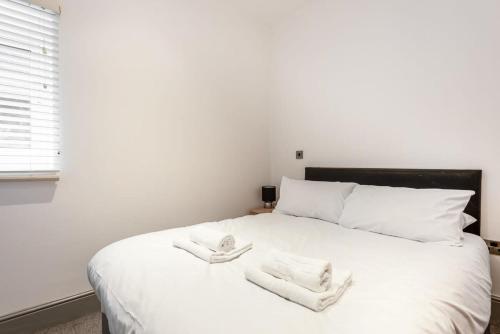 Un dormitorio con una cama blanca con toallas. en Modern 1 Bed Budget Apartment in Darlington en Darlington