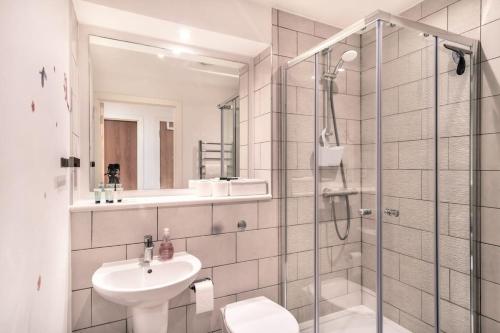 ein Bad mit einer Dusche, einem Waschbecken und einem WC in der Unterkunft Spacious & Modern 1 Bed Apartment Manchester in Manchester