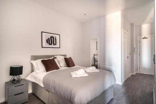 a white bedroom with a large bed with two towels on it at Modern & Spacious 2 Bed Apartment in Waterloo Liverpool in Waterloo