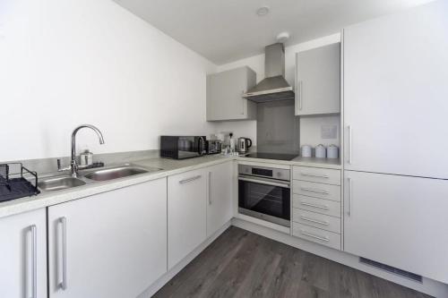 a white kitchen with white cabinets and a sink at Stylish and Bright 2 Bed Apartment in Ashford in Ashford