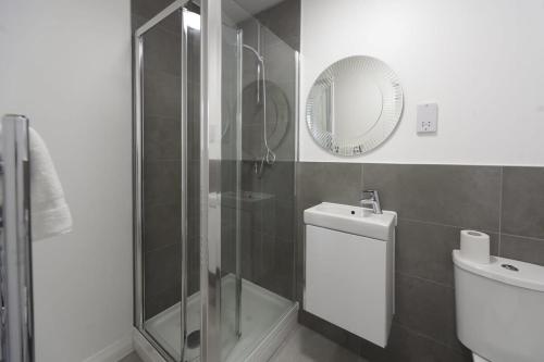 a bathroom with a shower and a toilet and a mirror at Stylish and Bright 2 Bed Apartment in Ashford in Ashford