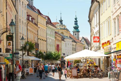 a group of people walking down a street with buildings at Cityhotel am Domplatz Self-CheckIn in Klagenfurt