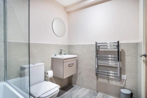 a bathroom with a toilet and a sink and a mirror at Spacious & Modern 2 Bed Apartment in Manchester in Manchester