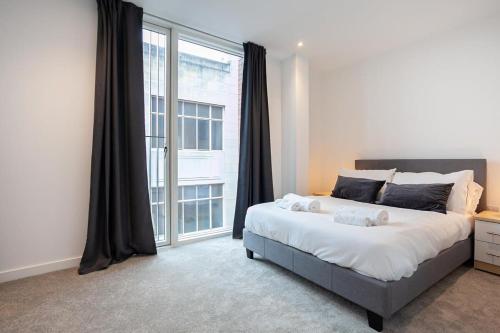 - une chambre avec un grand lit et une grande fenêtre dans l'établissement Spacious 2 Bed Apartment in Central Manchester, à Manchester