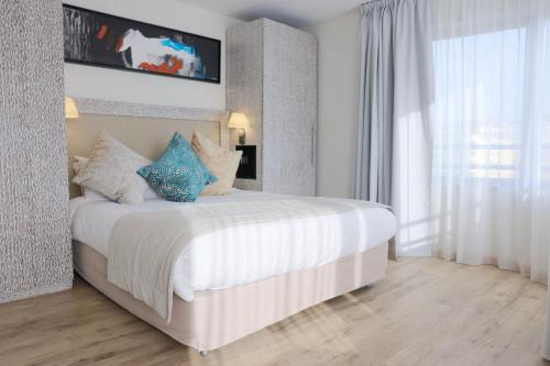 a bedroom with a large white bed with blue pillows at Eden Hotel & Spa in Cannes