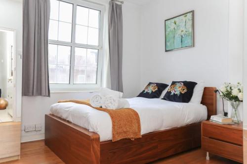 a bedroom with a bed with white sheets and a window at Lovely 2 Bedroom Apartment in Central London in London