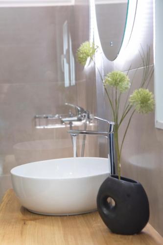 a bathroom with a white sink and a vase with flowers at Skyview Suites in Lefkada Town