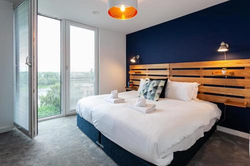 1 dormitorio con 1 cama grande y pared azul en Amazing 2 Bed Apartment 5min To Old Trafford, en Mánchester