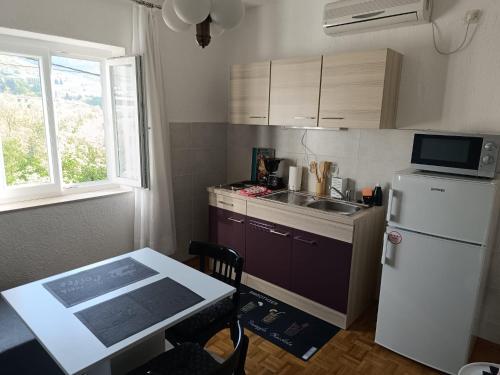 uma pequena cozinha com um frigorífico branco e uma mesa em Apartman Ena em Senj