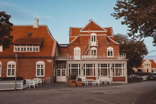 un grand bâtiment en briques avec des tables et des chaises blanches dans l'établissement Brøndums Hotel, à Skagen