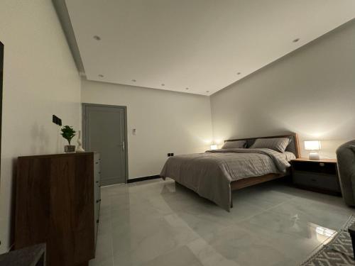 ein Schlafzimmer mit einem Bett, einer Kommode und zwei Lampen in der Unterkunft سويت انيق بقفل ذكي بحي العقيق in Riad