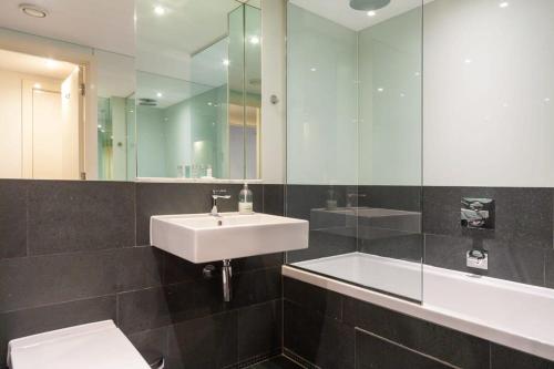 ein Badezimmer mit einem Waschbecken, einem WC und einem Spiegel in der Unterkunft Spacious and Modern 1 Bedroom Apartment in Chelsea in London
