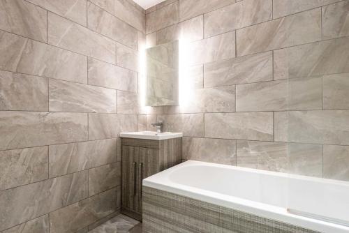 a bathroom with a bath tub and a sink at Modern 3 Bed Budget Apartment in Central Doncaster in Doncaster
