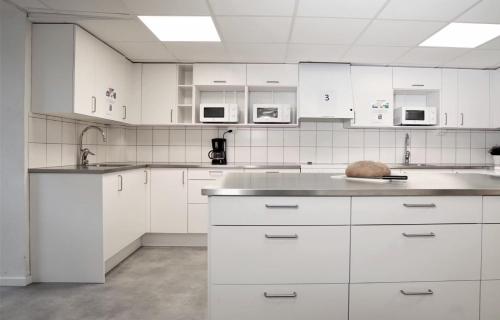 a white kitchen with white cabinets and a sink at Forenom Hostel Lund Örtofta in Eslöv