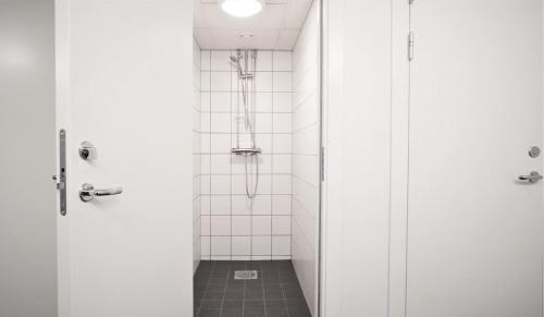 y baño con ducha de azulejos blancos. en Forenom Hostel Lund Örtofta, en Eslöv