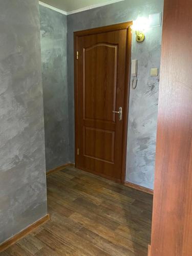 an empty room with a wooden door and wood floors at Тәуелсіздік 89, 1 комнатные апартаменты комфорт класса в центре от компании Home Hotel in Kostanay