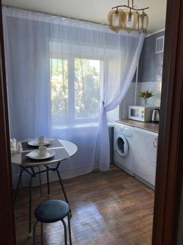 a small kitchen with a table and a microwave at Тәуелсіздік 89, 1 комнатные апартаменты комфорт класса в центре от компании Home Hotel in Kostanay