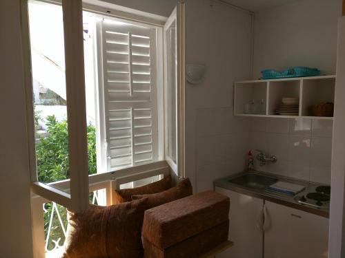 a kitchen with a window with a sink and a chair at Apartment Bugenvila in Vrboska