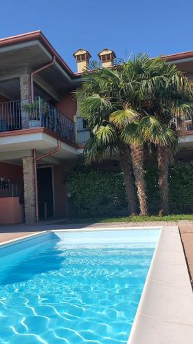 une maison avec des palmiers en face d'une piscine dans l'établissement Villa Lago 5, à Sirmione