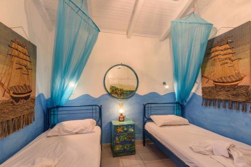 - 2 lits dans une chambre avec des rideaux bleus et un miroir dans l'établissement The Blue House Seaside Retreat - Fully equipped, à Chrani