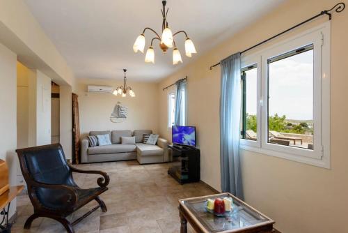 a living room with a couch and a tv at Porto Cheli Panoramic Poolside Getaway in Porto Heli