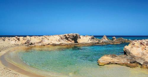 a beach with blue water and rocks at Malia Stone Residence - Secluded Cozy Retreat in Goníai