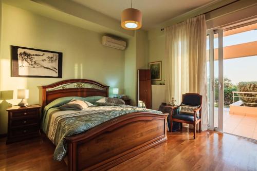 a bedroom with a bed and a chair and a window at Verga Sunset Villa - Ilia Seascape Private Retreat in Mikrá Mandínia