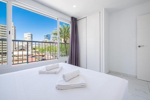 - une chambre avec un lit blanc et une grande fenêtre dans l'établissement Penthouse Ancla 561 Levante Beach, à Benidorm